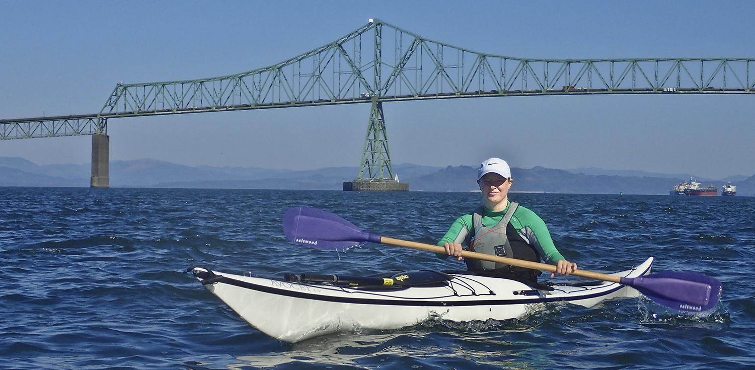 woman kayaks under the Youngs Bay Bridge