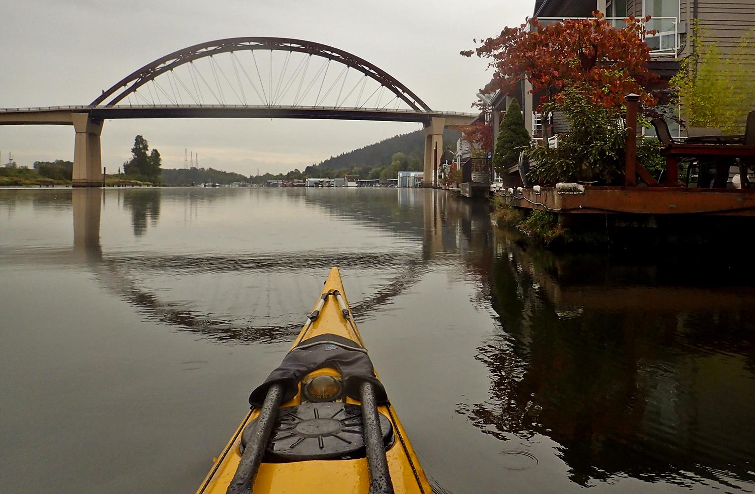 Kayak approaches the Sauvie Island Bridge, floating home on the right